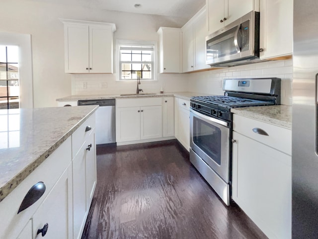 kitchen featuring sink, white cabinetry, stainless steel appliances, dark hardwood / wood-style floors, and light stone counters