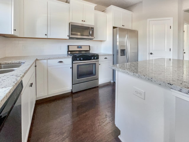 kitchen with backsplash, light stone countertops, white cabinets, and appliances with stainless steel finishes