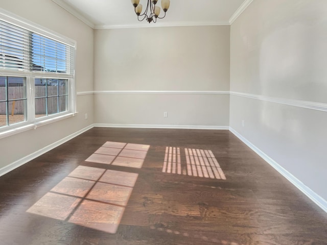 spare room featuring dark wood-type flooring, crown molding, and a chandelier