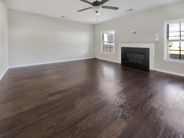 unfurnished living room with dark wood-type flooring, ceiling fan, and plenty of natural light