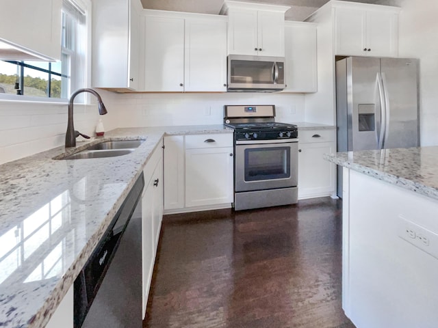 kitchen featuring sink, white cabinetry, backsplash, stainless steel appliances, and light stone countertops