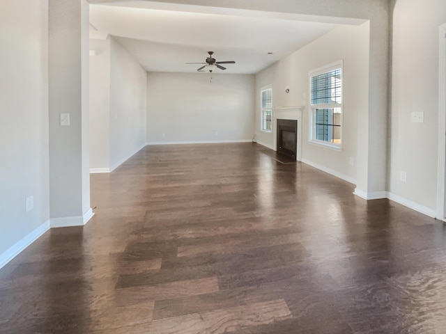 unfurnished living room with dark hardwood / wood-style flooring and ceiling fan