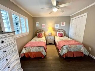 bedroom featuring dark wood-type flooring, a closet, ornamental molding, and ceiling fan