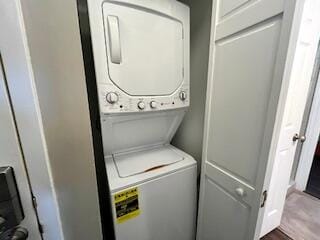 clothes washing area with hardwood / wood-style flooring and stacked washing maching and dryer