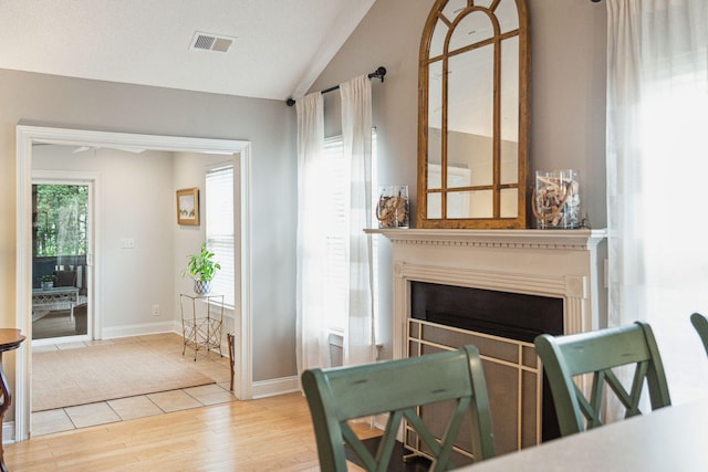 living room featuring a textured ceiling, light wood-type flooring, and vaulted ceiling