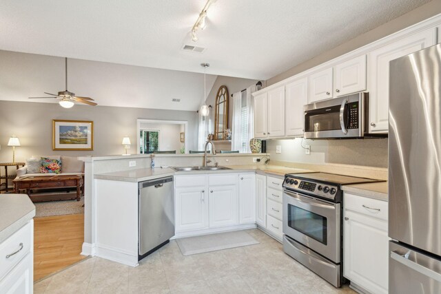 kitchen featuring appliances with stainless steel finishes, kitchen peninsula, white cabinetry, and sink