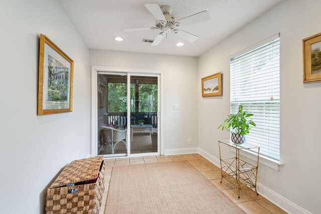 entryway featuring ceiling fan, light tile patterned flooring, a textured ceiling, and a healthy amount of sunlight