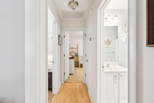 corridor with light wood-type flooring and sink