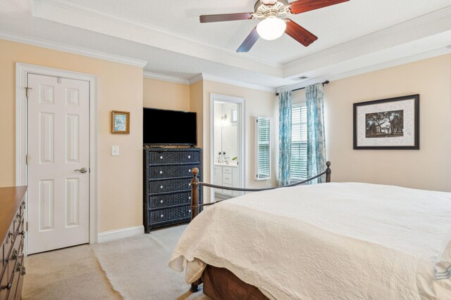 carpeted bedroom featuring ornamental molding, ensuite bath, ceiling fan, and a tray ceiling