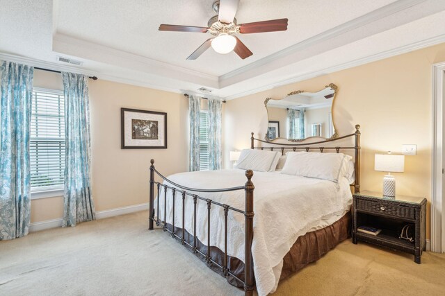 bedroom with a raised ceiling, ceiling fan, light colored carpet, and crown molding