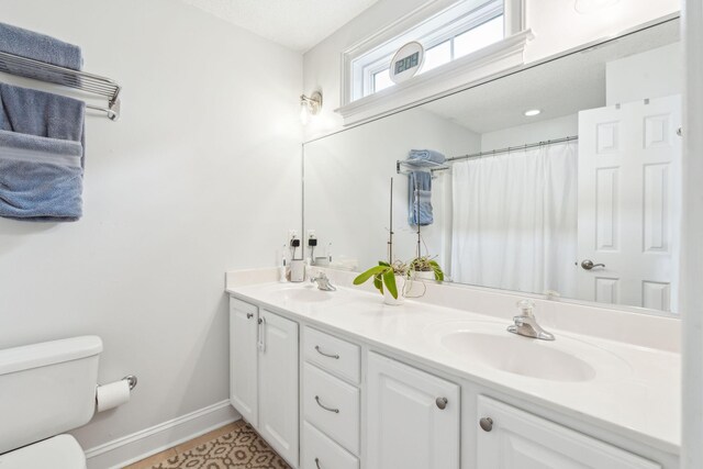 bathroom with curtained shower, vanity, and toilet