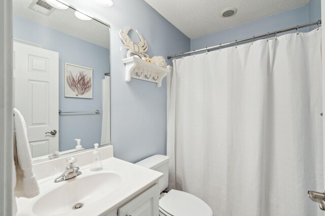 bathroom with vanity, toilet, a textured ceiling, and curtained shower