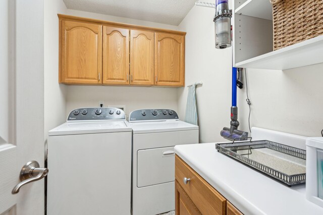 laundry area with a textured ceiling, independent washer and dryer, and cabinets