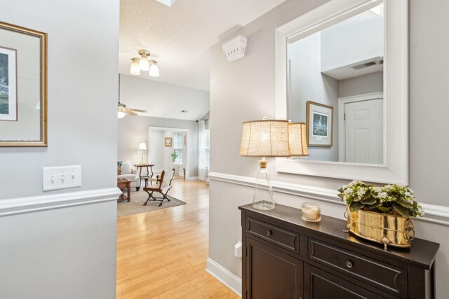 hallway with light wood-type flooring and a textured ceiling