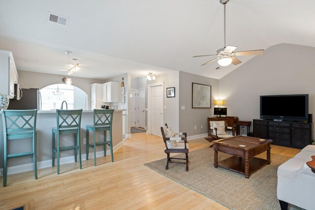 living room featuring vaulted ceiling, ceiling fan, and light hardwood / wood-style flooring