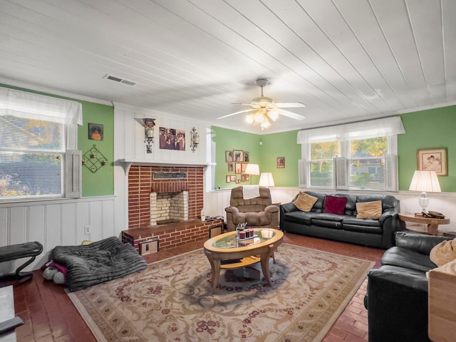 living room featuring a brick fireplace, ceiling fan, and ornamental molding