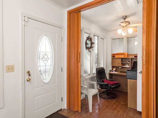 foyer entrance with ornamental molding and ceiling fan