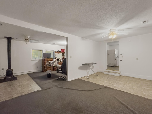 1104 2nd Ave, Kingstree, SC 29556 - spare room with a ceiling fan, a wood stove, a textured ceiling, and carpet floors
