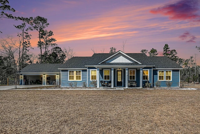 view of front of property with covered porch, roof with shingles, an attached garage, and a front lawn