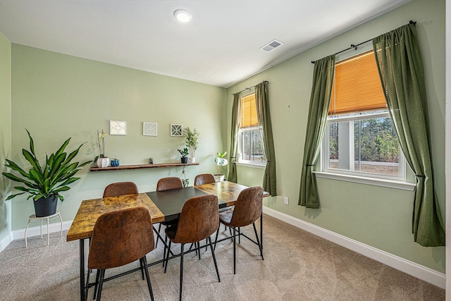 carpeted dining room with visible vents and baseboards