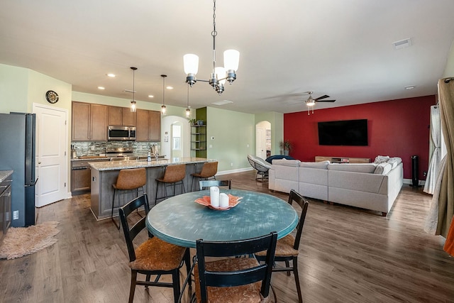 dining space featuring arched walkways, visible vents, dark wood finished floors, and baseboards