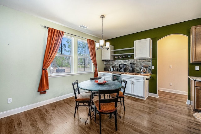 dining space with baseboards, arched walkways, visible vents, dark wood-style flooring, and a chandelier