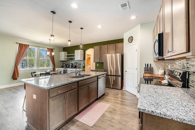 kitchen with light wood-style flooring, a sink, visible vents, appliances with stainless steel finishes, and light stone countertops