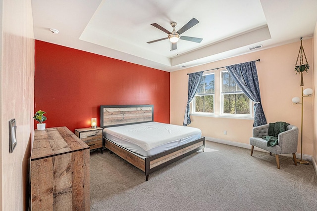 bedroom with carpet, a raised ceiling, visible vents, and baseboards