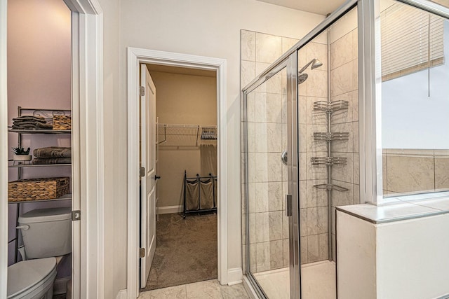 bathroom featuring a shower stall, toilet, and a walk in closet