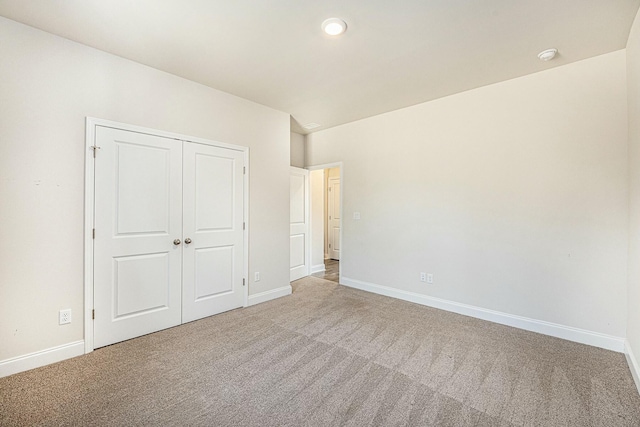 unfurnished bedroom with baseboards, a closet, and light colored carpet