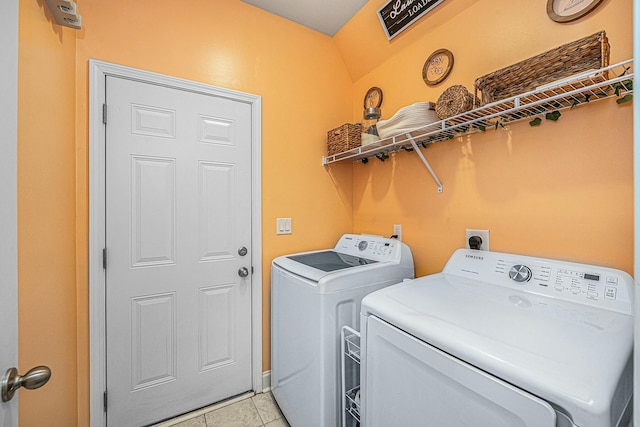 clothes washing area featuring laundry area, washer and clothes dryer, and light tile patterned flooring