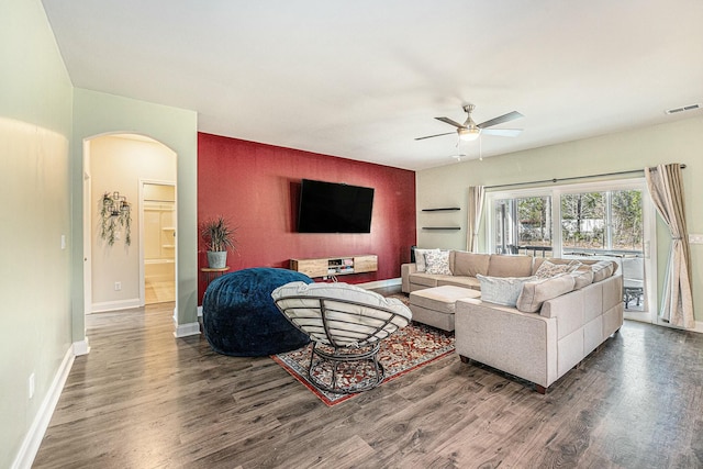 living room featuring arched walkways, visible vents, ceiling fan, wood finished floors, and baseboards