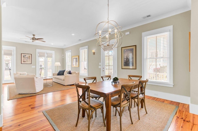 dining space featuring ceiling fan with notable chandelier, baseboards, visible vents, light wood-style floors, and ornamental molding