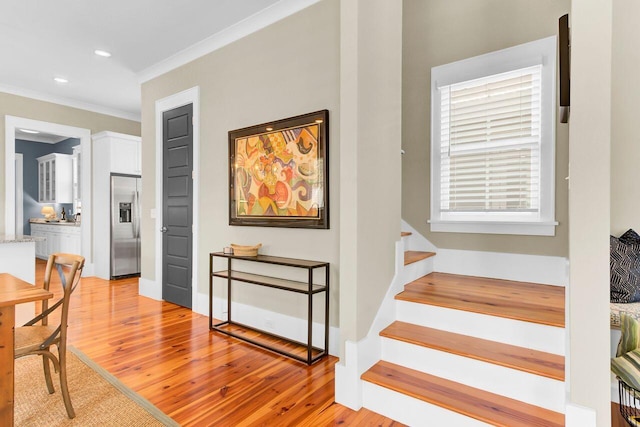 stairs with baseboards, wood finished floors, recessed lighting, and crown molding