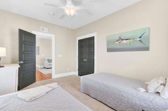 bedroom featuring baseboards, ceiling fan, visible vents, and light colored carpet