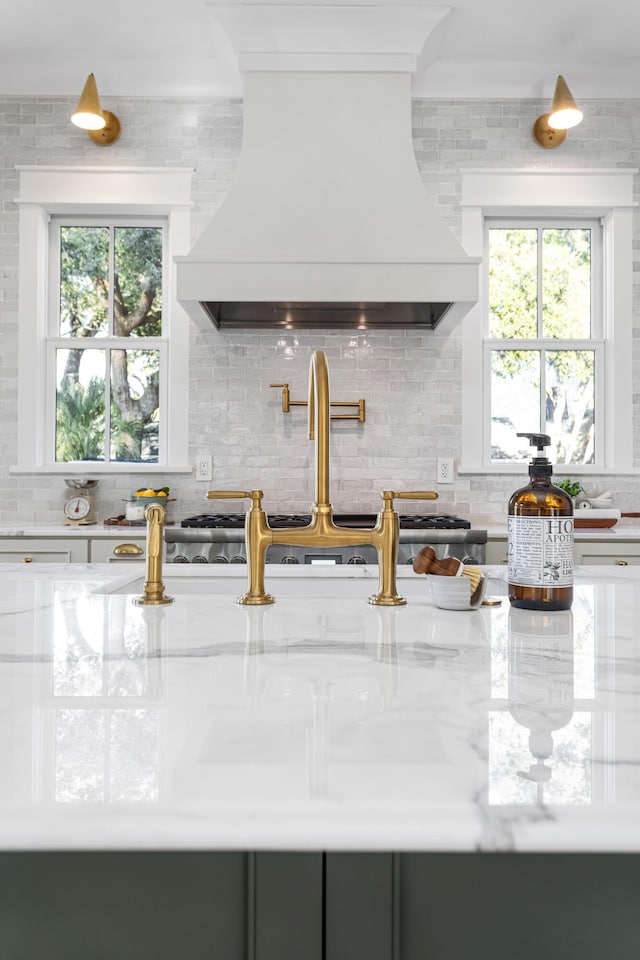 kitchen with sink, decorative backsplash, light stone countertops, and premium range hood