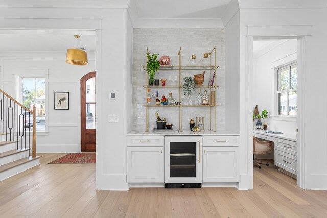 bar featuring light hardwood / wood-style flooring, white cabinetry, wine cooler, ornamental molding, and decorative light fixtures