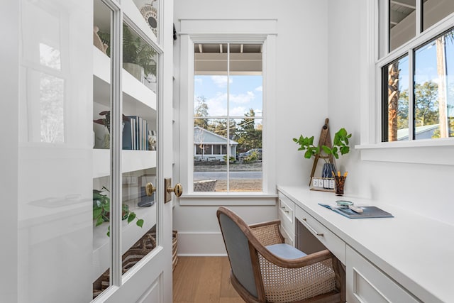 home office featuring built in desk, light hardwood / wood-style flooring, and a wealth of natural light