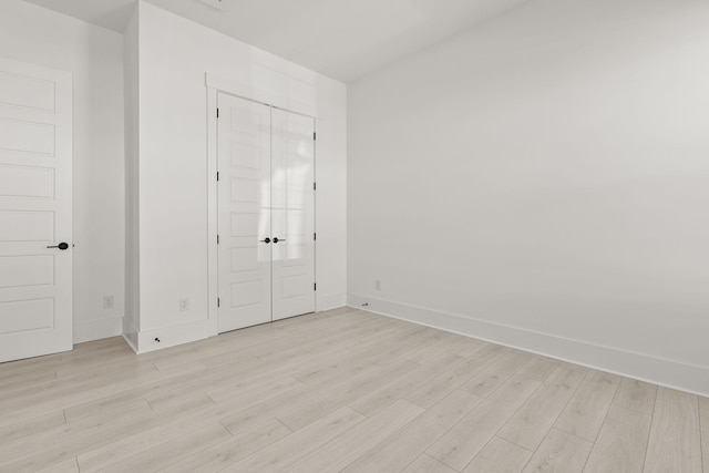 unfurnished bedroom with a closet, light wood-style flooring, and baseboards