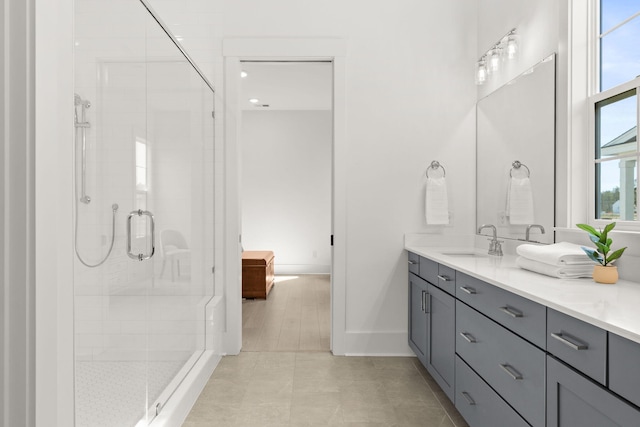 full bathroom with a stall shower, tile patterned floors, baseboards, and vanity