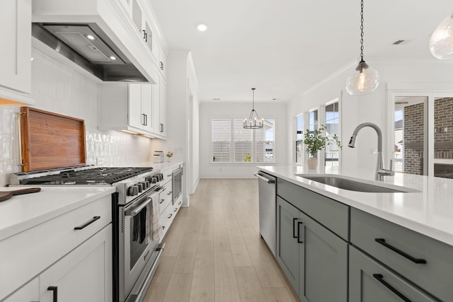 kitchen featuring stainless steel appliances, a sink, light countertops, custom exhaust hood, and pendant lighting