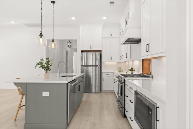 kitchen featuring decorative backsplash, an island with sink, appliances with stainless steel finishes, light countertops, and a sink