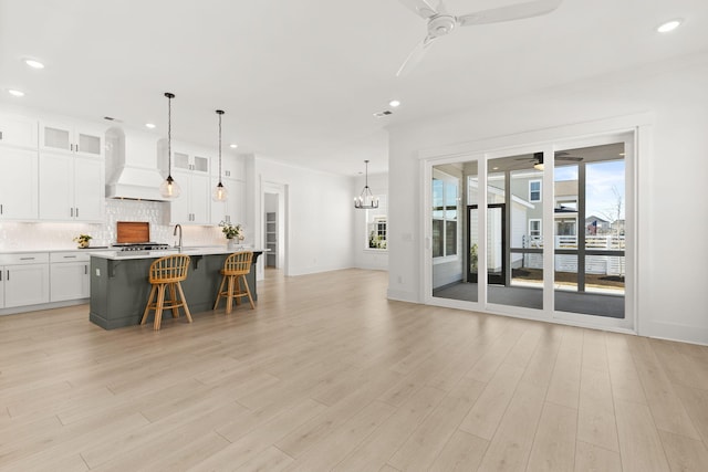 kitchen featuring a kitchen bar, custom exhaust hood, backsplash, and ceiling fan with notable chandelier