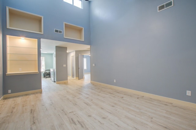 empty room featuring a towering ceiling and light hardwood / wood-style floors