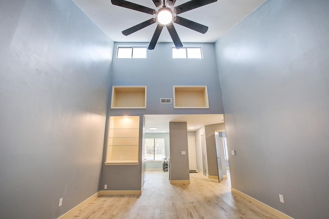 interior space with a towering ceiling, light hardwood / wood-style floors, and ceiling fan