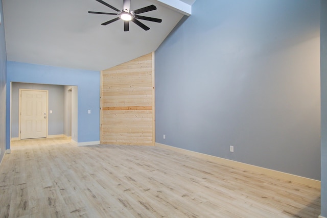 spare room featuring ceiling fan, wooden walls, vaulted ceiling, and light wood-type flooring