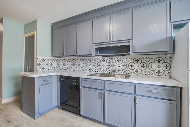 kitchen featuring sink, gray cabinetry, light hardwood / wood-style flooring, black dishwasher, and decorative backsplash