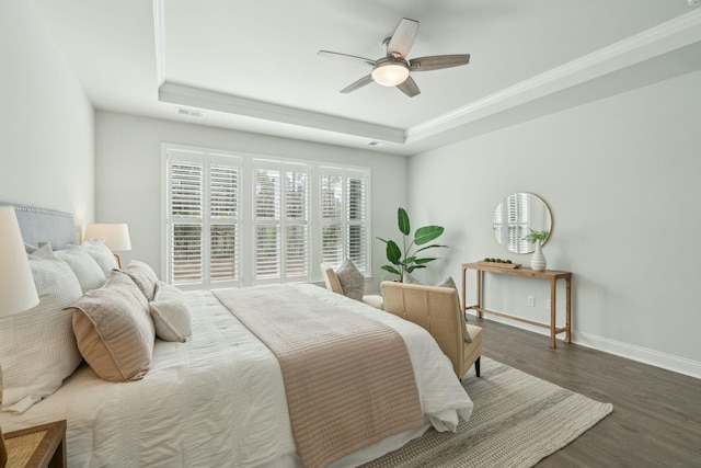 bedroom featuring wood finished floors, a raised ceiling, visible vents, and baseboards