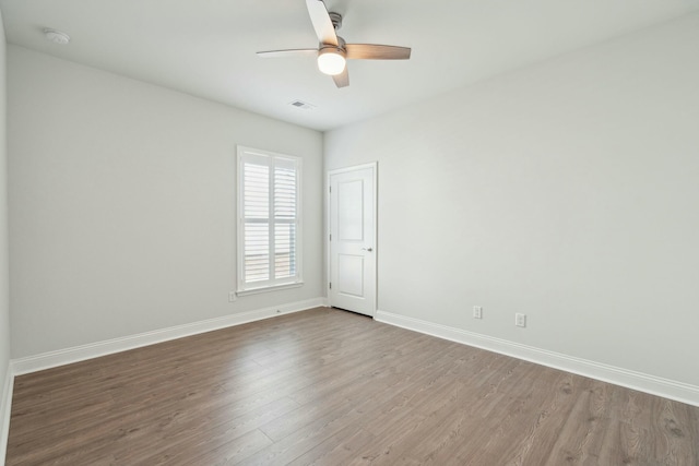 spare room with a ceiling fan, baseboards, visible vents, and wood finished floors