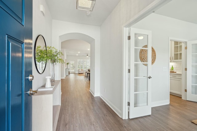 foyer featuring arched walkways, wood finished floors, and baseboards